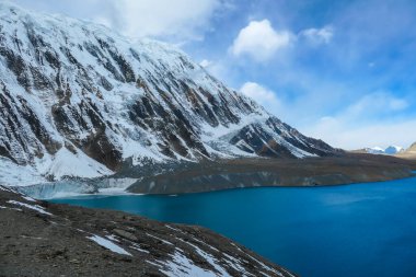 A panoramic view on turquoise colored Tilicho lake in Himalayas, Manang region in Nepal. The world's highest altitude lake (4949m). Snow capped mountains around. Calm surface of the lake. Serenity