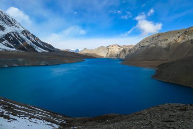 A panoramic view on turquoise colored Tilicho lake in Himalayas, Manang region in Nepal. The world's highest altitude lake (4949m). Snow capped mountains around. Calm surface of the lake. Serenity