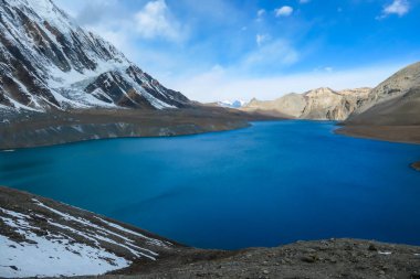 A panoramic view on turquoise colored Tilicho lake in Himalayas, Manang region in Nepal. The world's highest altitude lake (4949m). Snow capped mountains around. Calm surface of the lake. Serenity