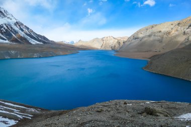 A panoramic view on turquoise colored Tilicho lake in Himalayas, Manang region in Nepal. The world's highest altitude lake (4949m). Snow capped mountains around. Calm surface of the lake. Serenity