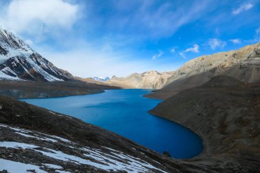 A panoramic view on turquoise colored Tilicho lake in Himalayas, Manang region in Nepal. The world's highest altitude lake (4949m). Snow capped mountains around. Calm surface of the lake. Serenity