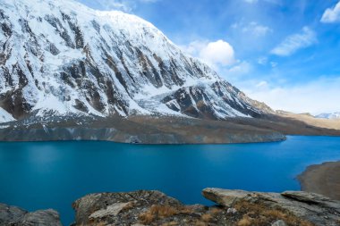 A panoramic view on turquoise colored Tilicho lake in Himalayas, Manang region in Nepal. The world's highest altitude lake (4949m). Snow capped mountains around. Calm surface of the lake. Serenity