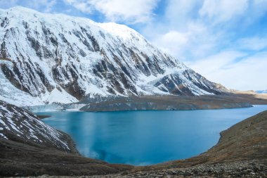 A panoramic view on turquoise colored Tilicho lake in Himalayas, Manang region in Nepal. The world's highest altitude lake (4949m). Snow capped mountains around. Calm surface of the lake. Serenity