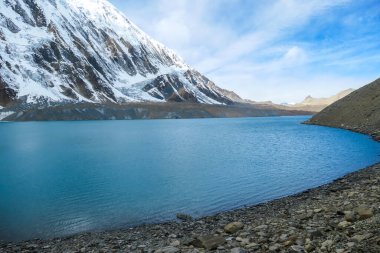 A panoramic view on turquoise colored Tilicho lake in Himalayas, Manang region in Nepal. The world's highest altitude lake (4949m). Snow capped mountains around. Calm surface of the lake. Serenity