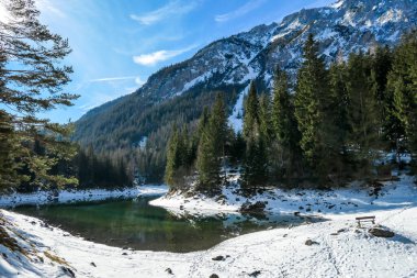 Winter landscape of Austrian Alps with Green Lake in the middle. Powder snow covering the mountains and ground. Soft reflections of Alps in calm lake's water. Winter wonderland. Serenity and calmness