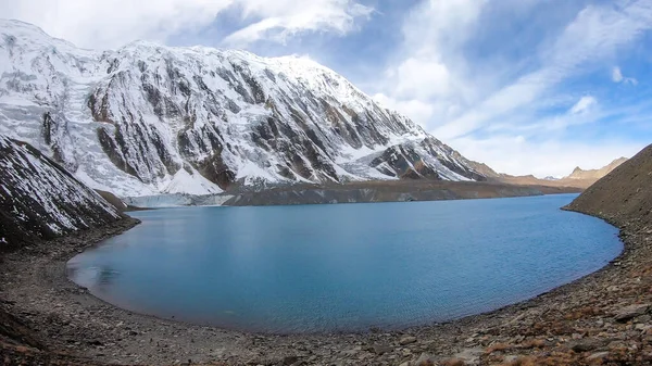 A panoramic view on turquoise colored Tilicho lake in Himalayas, Manang region in Nepal. The world's highest altitude lake (4949m). Snow capped mountains around. Calm surface of the lake. Serenity