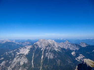 A panoramic view on endless mountain chains from top of a mountain in Hochtor region, Austrian Alps. High Alpine mountaineering. Sunny, cloudless summer day. Exploring new places.