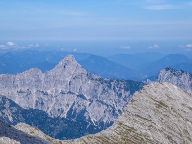A panoramic view on endless mountain chains from top of a mountain in Hochtor region, Austrian Alps. High Alpine mountaineering. Sunny, cloudless summer day. Sharp and stony slopes in the foreground.