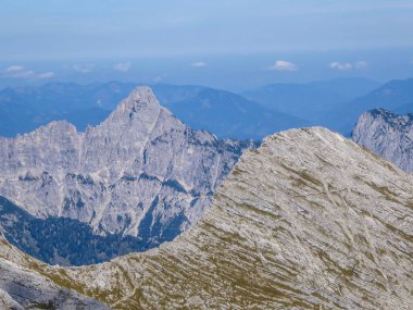 A panoramic view on endless mountain chains from top of a mountain in Hochtor region, Austrian Alps. High Alpine mountaineering. Sunny, cloudless summer day. Sharp and stony slopes in the foreground.