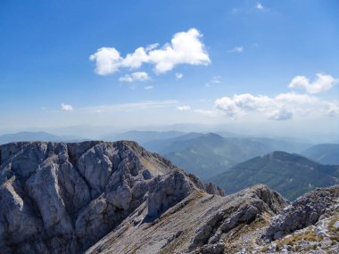 A panoramic view on a massive, stony mountains in Hochturm region, Austrian Alps. There are endless mountains chains in the back. The slopes are overgrown with moss and grass. Sunny and bright day.