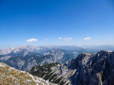 A panoramic view on a massive, stony mountains in Hochturm region, Austrian Alps. There are endless mountains chains in the back. The slopes are overgrown with moss and grass. Sunny and bright day.