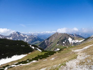 A panoramic view on a massive, stony mountains in Hochturm region, Austrian Alps. There are endless mountains chains in the back. The slopes are overgrown with moss and grass. Sunny and bright day.