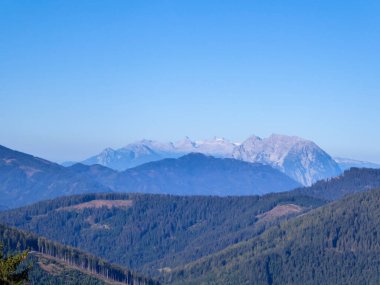A panoramic view on a massive, stony Alps from Kaiserau Kreuzkogel region in Austria. There are endless mountains chains in the back. The slopes are overgrown with moss and grass. Sunny and bright day