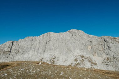 A panoramic view on the plain on top of a mountain in Hochschwab region in Austrian Alps. The flora overgrowing the slopes is turning golden. Autumn vibes. Many mountain chains in the back. Wilderness