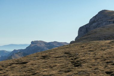 A panoramic view on the plain on top of a mountain in Hochschwab region in Austrian Alps. The flora overgrowing the slopes is turning golden. Autumn vibes. Many mountain chains in the back. Wilderness