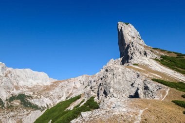 A view on a massive mountain wall in Alps in Hochschwab region, Austria. The slopes are really steep and dangerous to climb. Rocky landscape. Golden grass, autumn vibes. Freedom and wilderness
