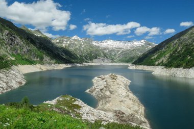 Dam in Austrian Alps. The artificial lake stretches over a vast territory, shining with navy blue color. The dam is surrounded by high mountains. In the back there is a glacier. Controlling the nature clipart