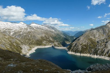 Dam in Austrian Alps. The artificial lake stretches over a vast territory, shining with navy blue color. The dam is surrounded by high mountains. In the back there is a glacier. Controlling the nature clipart