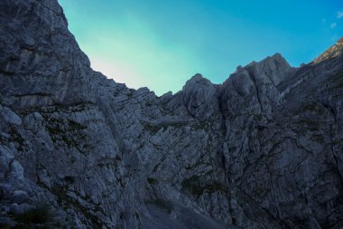 A panoramic view on Alpine slopes in Austria. There are sharp ans steep mountains and high peaks around. The Alpine slopes are almost barren, just moss overgrowing the slopes. Serenity and freedom.