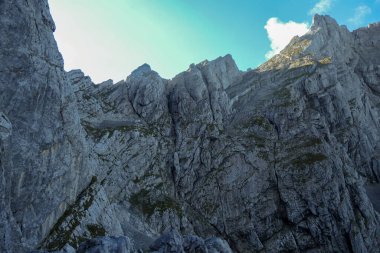 A panoramic view on Alpine slopes in Austria. There are sharp ans steep mountains and high peaks around. The Alpine slopes are almost barren, just moss overgrowing the slopes. Serenity and freedom.