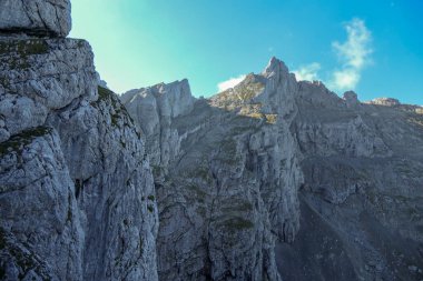 A panoramic view on Alpine slopes in Austria. There are sharp ans steep mountains and high peaks around. The Alpine slopes are almost barren, just moss overgrowing the slopes. Serenity and freedom.