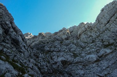 A panoramic view on Alpine slopes in Austria. There are sharp ans steep mountains and high peaks around. The Alpine slopes are almost barren, just moss overgrowing the slopes. Serenity and freedom.