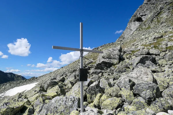 A wooden cross on top of Arlhoehe in Maltal region in Austrian Alps. The cross is surrounded by lose stones and boulders. Summer in the mountains. Serenity and achievement.