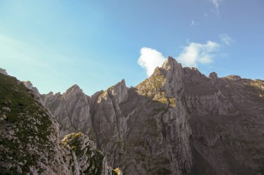 A panoramic view on Alpine slopes in Austria. There are sharp ans steep mountains and high peaks around. The Alpine slopes are almost barren, just moss overgrowing the slopes. Serenity and freedom.