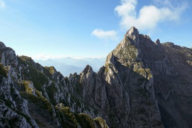A panoramic view on Alpine slopes in Austria. There are sharp ans steep mountains and high peaks around. The Alpine slopes are almost barren, just moss overgrowing the slopes. Serenity and freedom.