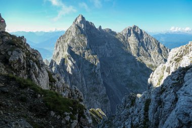A panoramic view on Alpine slopes in Austria. There are sharp ans steep mountains and high peaks around. The Alpine slopes are almost barren, just moss overgrowing the slopes. Serenity and freedom.