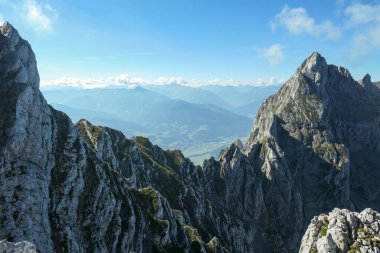 A panoramic view on Alpine slopes in Austria. There are sharp ans steep mountains and high peaks around. The Alpine slopes are almost barren, just moss overgrowing the slopes. Serenity and freedom.