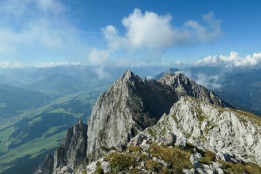 A panoramic view on Alpine slopes in Austria. There are sharp ans steep mountains and high peaks around. The Alpine slopes are almost barren, just moss overgrowing the slopes. Serenity and freedom.