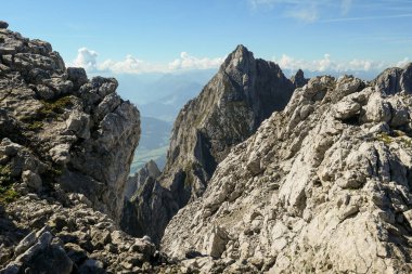 A panoramic view on Alpine slopes in Austria. There are sharp ans steep mountains and high peaks around. The Alpine slopes are almost barren, just moss overgrowing the slopes. Serenity and freedom.