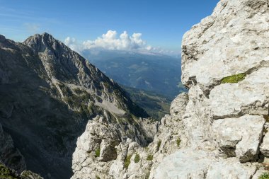 A panoramic view on Alpine slopes in Austria. There are sharp ans steep mountains and high peaks around. The Alpine slopes are almost barren, just moss overgrowing the slopes. Serenity and freedom.