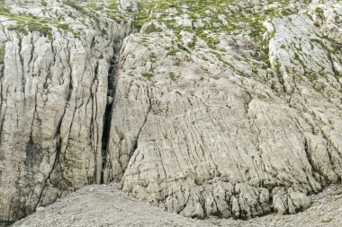 A steep mountain wall on the way to Grimming in Austrian Alps. Dangerous climbing only for professionals. The sky above it is blue, one small cloud. Extreme sport. red path mark on the side.