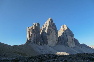 Capture of the Tre Cime di Lavaredo (Drei Zinnen) in Italian Dolomites. The mountains are catching the first sunbeams of the day. There is a lot of landslides. Natural wonder. Discovery and adventure