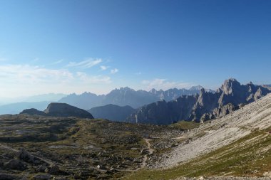 A view on a vast valley in Italian Dolomites. The valley is surrounded with high and sharp mountains from each side. Morning sun warms the valley up. Remote and isolated place. Remedy