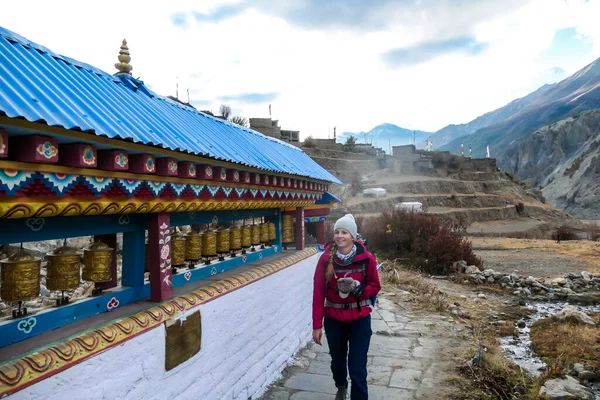 尼泊尔喜马拉雅山Annapurna环路旅行中 一个女人沿着满是祈祷轮的墙走着 这个女人喜欢长途跋涉 有一个高喜马拉雅山链在后面 精神和冥想 — 图库照片