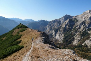 Woman hiking along a mountain ridge in Hochschwab region in Austrian Alps. Endless mountain chains in front. Massive Alps. Autumn vibes in the mountains. Idyllic landscape. Freedom and wilderness