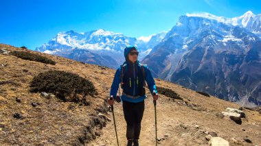 A man trekking on the Annapurna Circuit Trek, Himalayas, Nepal. Panoramic view on snow caped Annapurna chain. Lots of dried grass. High altitude, massive mountains. Freedom and adventure