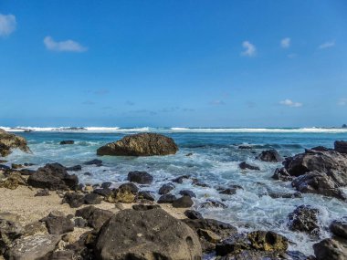 Waves splashing over dark stones in Sengigi beach on the island of Lombok (next to Bali) in Indonesia.