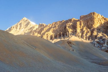 Himalayas Mountain Range, Annapurna Circuit Trek, Nepal. Clear sky above the peaks. Slopes covered with limestone rocks. Serene landscape. Dangerous mountains. Morning sun comes to the high parts