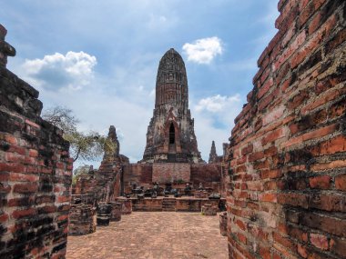 Ayutthaya temple complex in Thailand. Buildings constructed from red bricks. Bricks dirty from smoke. Temple gradually being destroyed. Passed times spirit can be felt. Desolated place.