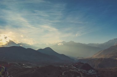 Sunlight wins over clouds above the Himalayan Peaks, Annapurna Circuit Trek, Nepal. Slopes covered with mist. Sharp slopes. In the Valley Muktinath city. Whole place gets ready for the coming night