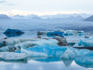 A melting glacier cap. Ice colored in many shades of blue. Big icebergs slowly drifting towards the sea. The effect of global warming. Disappearance of glaciers. Natural calamity. High mountain range.