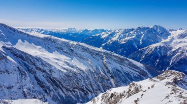 A beautiful and serene landscape of mountains covered with snow. Thick snow covers the slopes. Clear weather. Sharp slopes of the mountains covered with snow, with partially visible rocks.