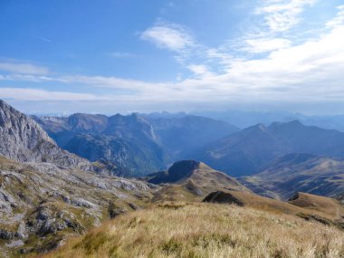 A hiking trail in the high mountain peaks. Lush green grass covers the slopes. Some crocuses are blossoming. Spring in the mountains. Nature wakes up after the hibernation period. Beautiful day.