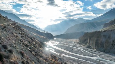 Way to Upper Pisang, Annapurna Circuit Trek, Nepal. Clear sky above the peak. Picturesque landscape, river in the bottom on the valley, small trees on the shores. White Himalayas mountain peaks