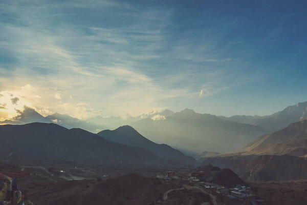 Sunlight wins over clouds above the Himalayan Peaks, Annapurna Circuit Trek, Nepal. Slopes covered with mist. Sharp slopes. In the Valley Muktinath city. Whole place gets ready for the coming night