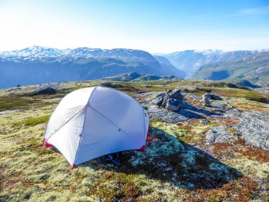 A tent located on a meadow, high in the mountains with the view on Eidfjord, Norway. Camping in the wilderness. Adventurous travels, living life to the fullest. Freedom and relax